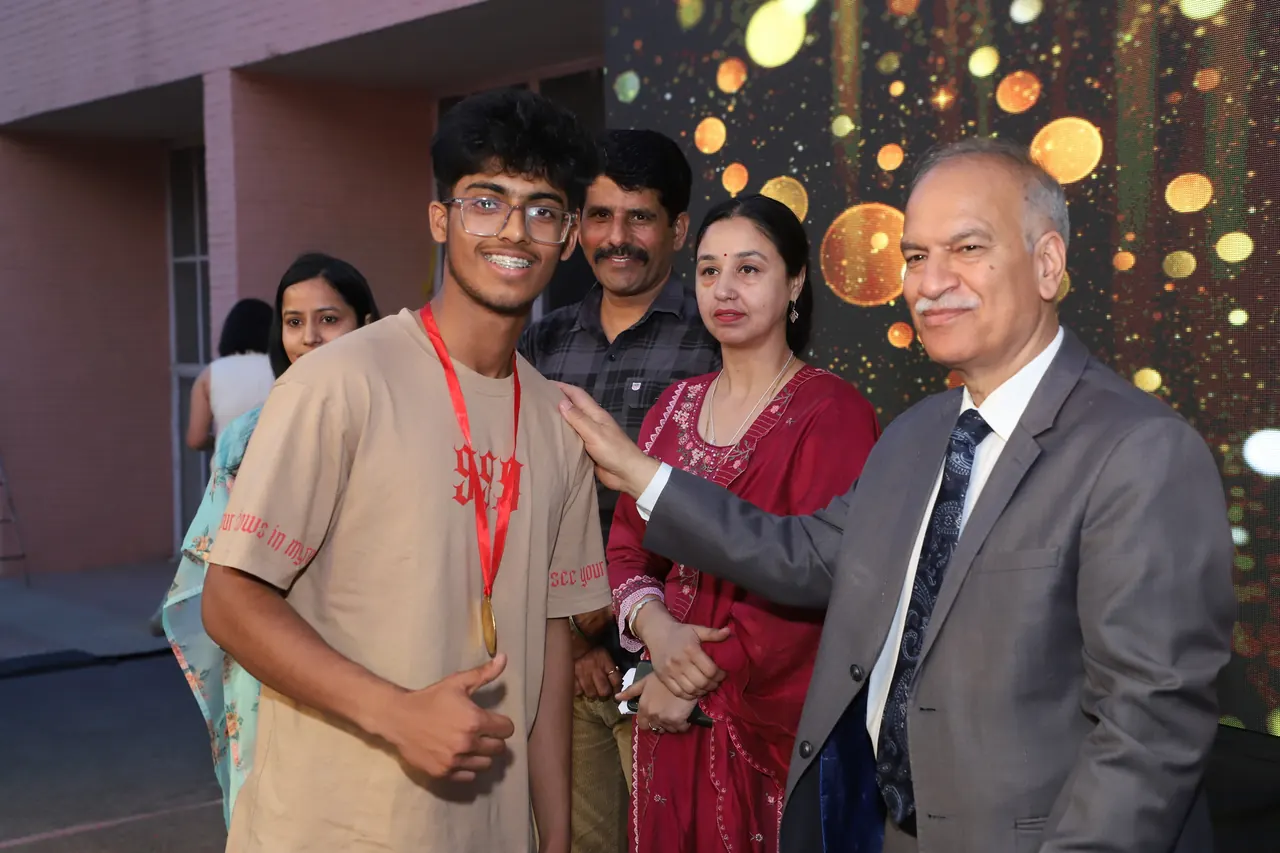 A medal winner gives a thumbs-up beside the guests