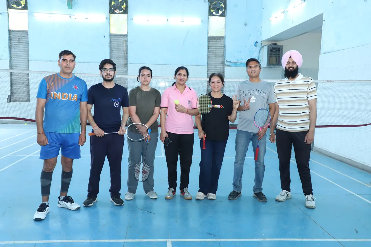 Badminton players line up together on the indoor court