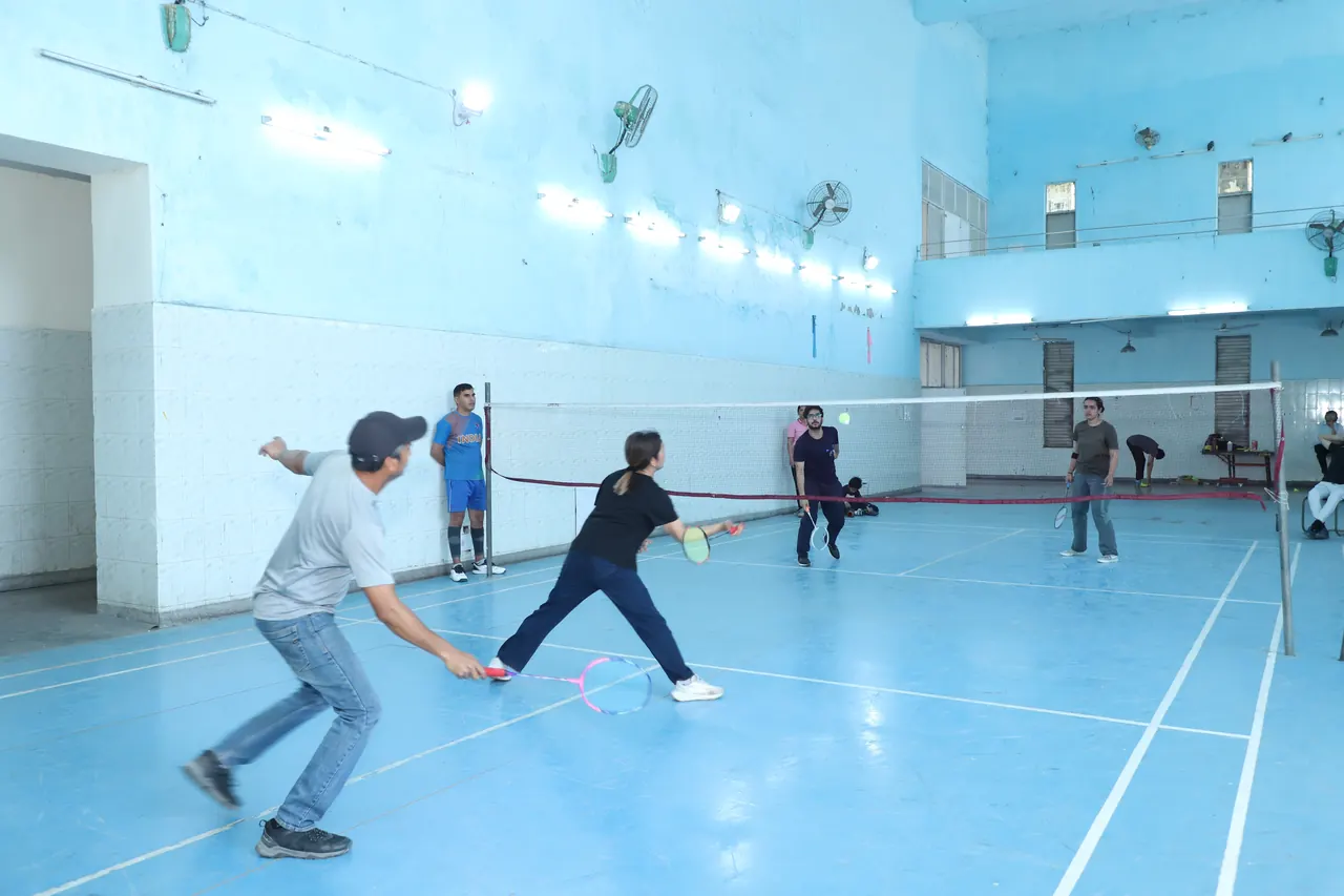 Badminton players lunge for shots in the indoor hall