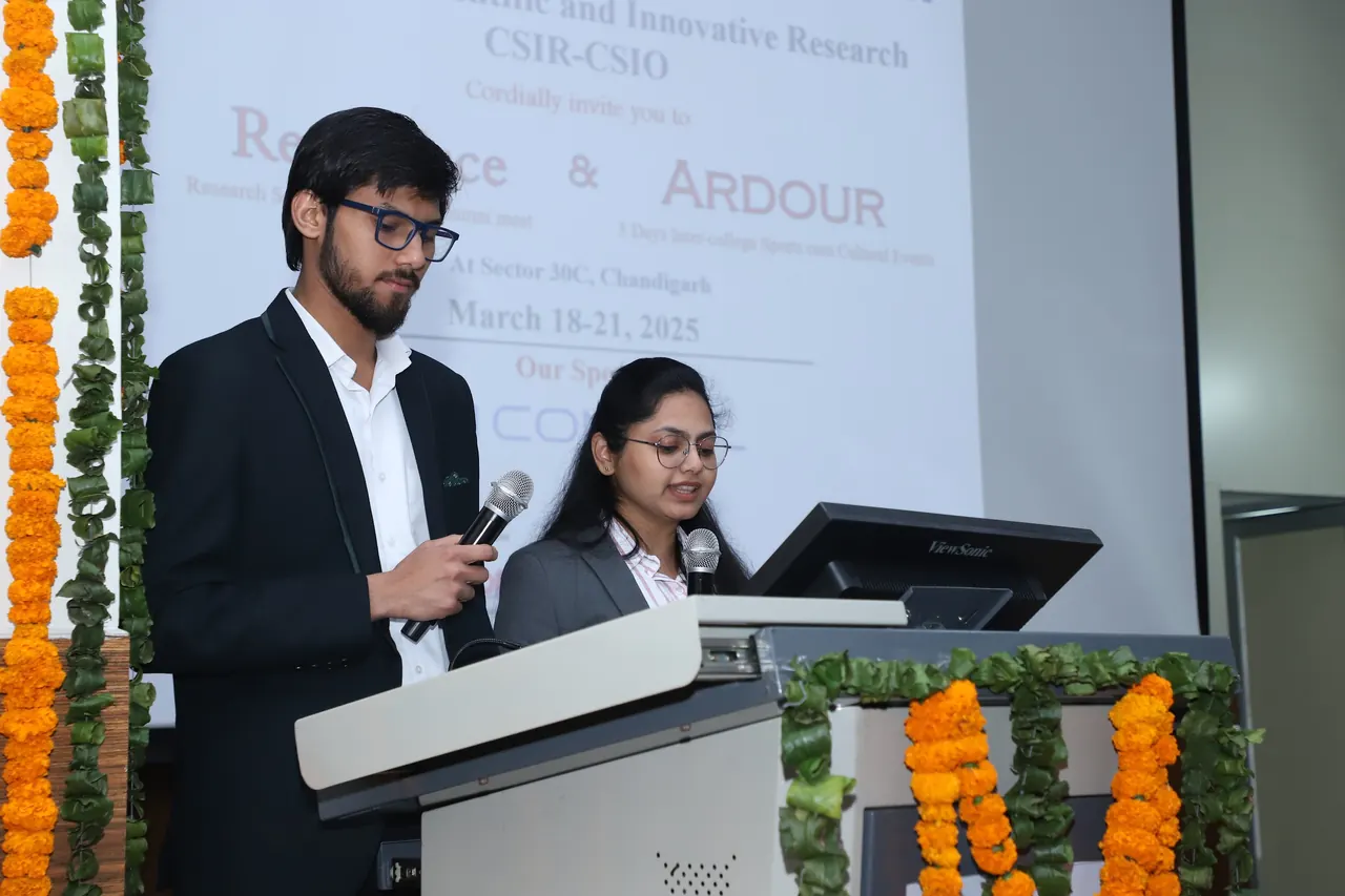 Two hosts speak at the podium in the auditorium