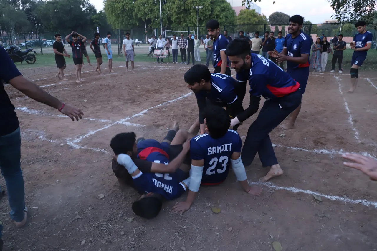 A kabaddi raider is brought down by a pile of defenders