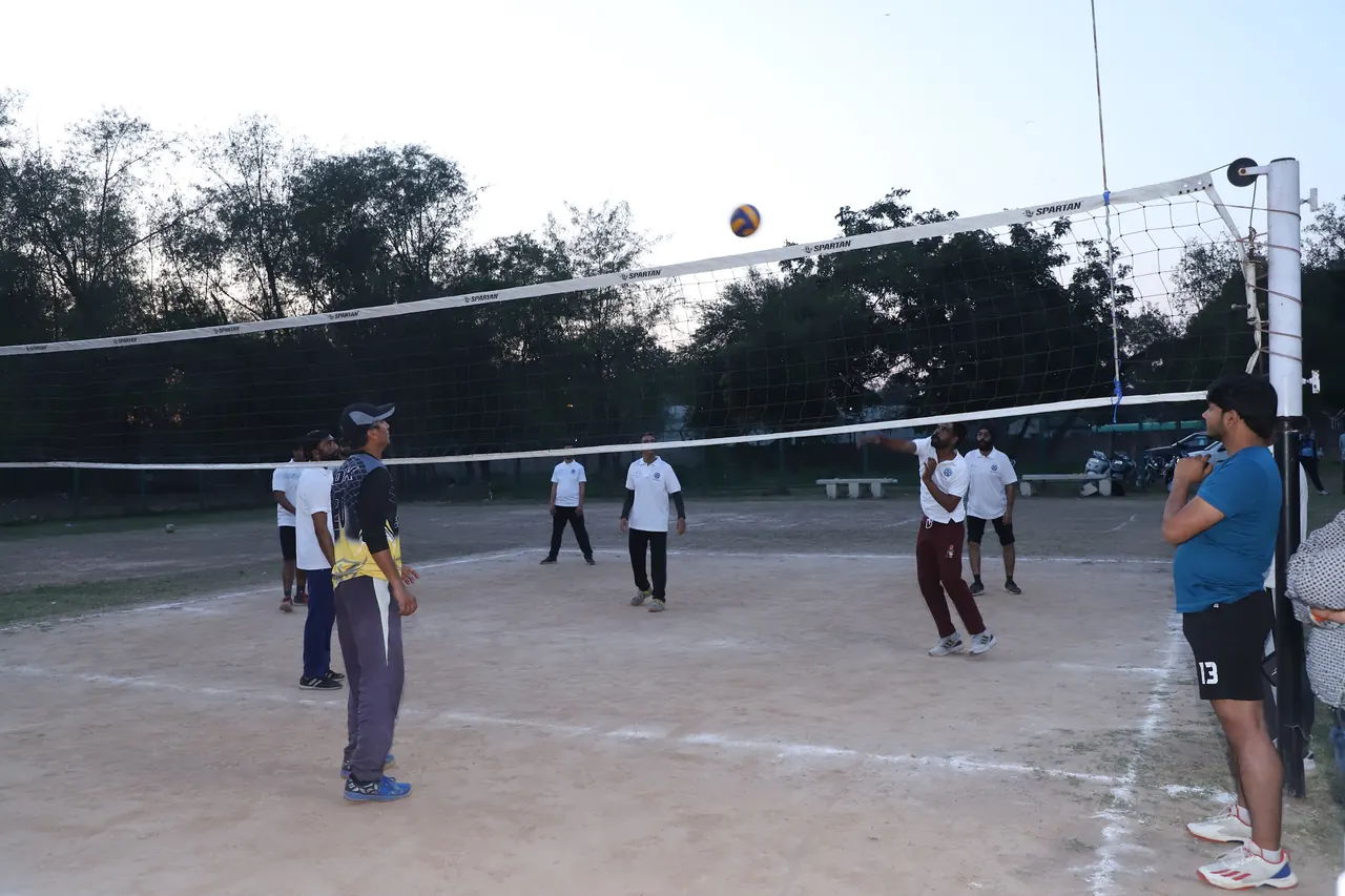 Volleyball players in position as the ball crosses the net in the evening
