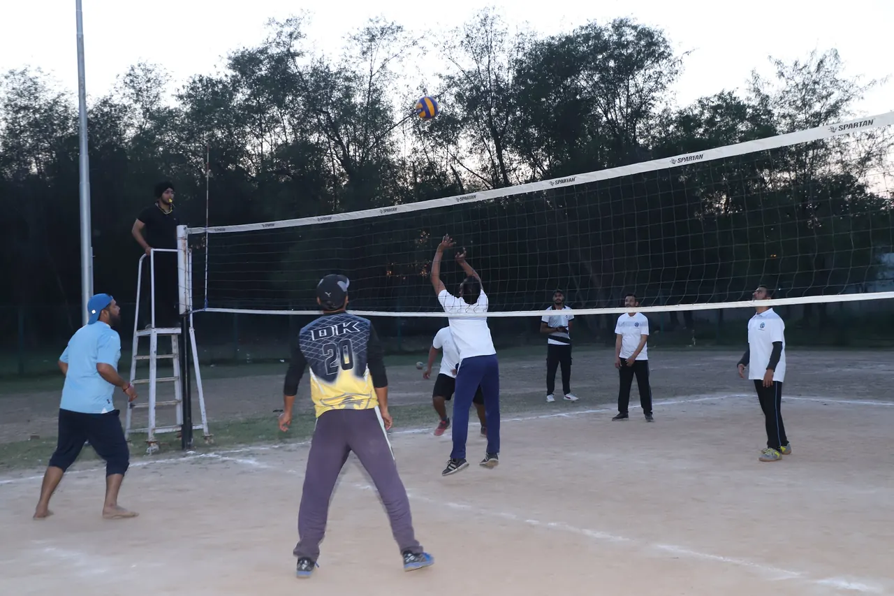 A volleyball player jumps at the net under floodlights