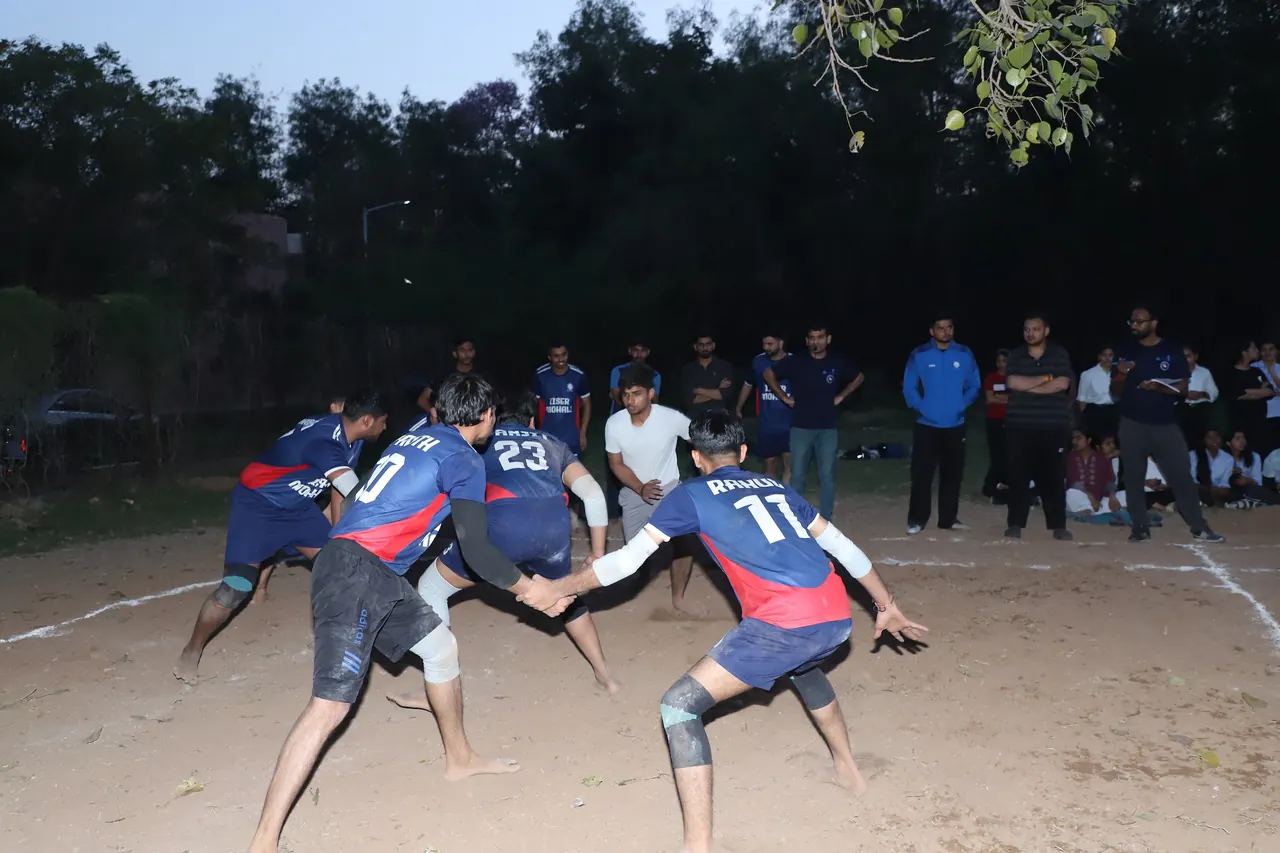 Kabaddi players grapple at dusk