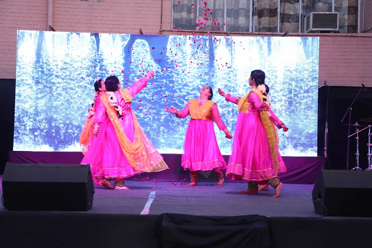 Dancers in pink skirts twirl in front of a winter-scene backdrop