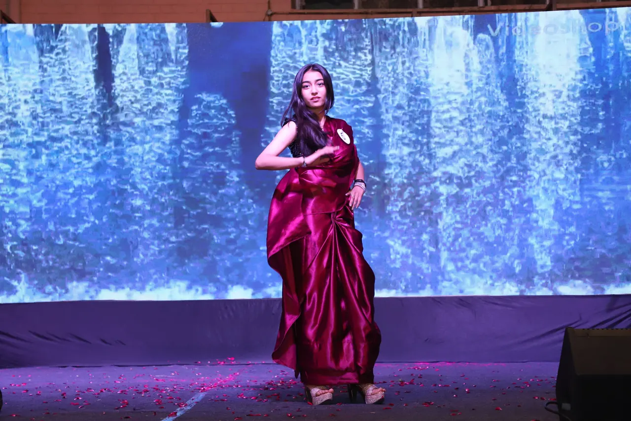 A participant in a red saree walks the ramp
