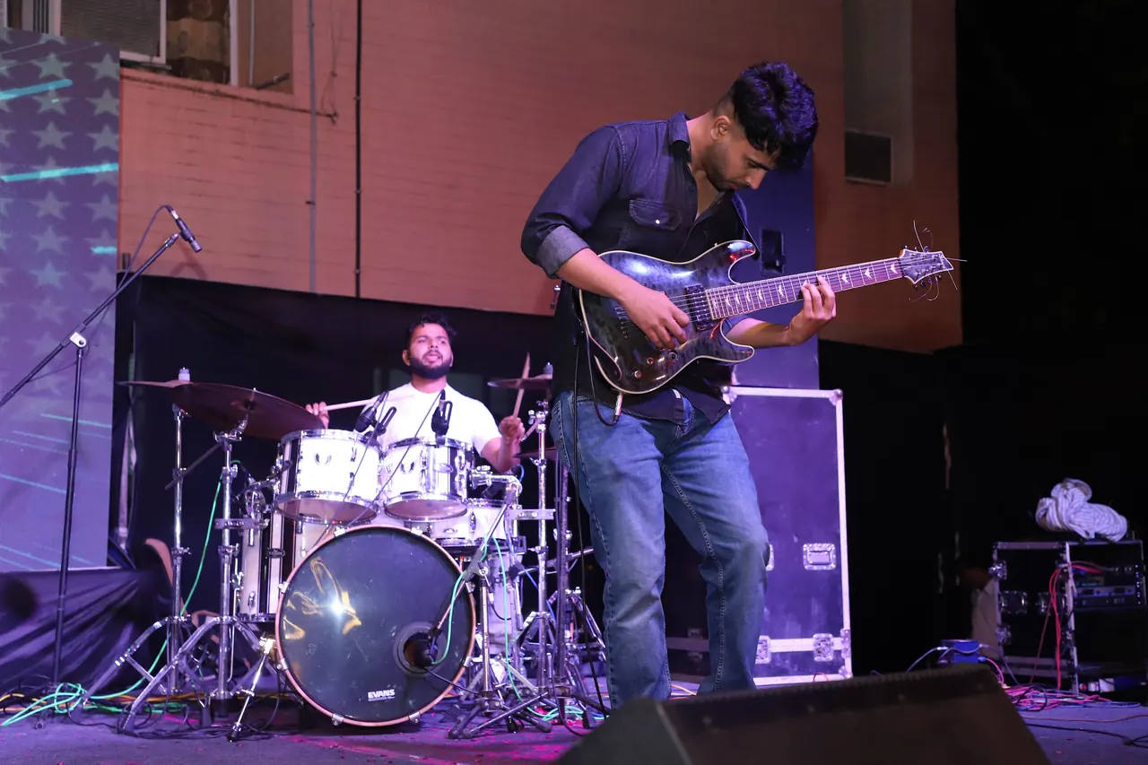 A guitarist and drummer play on the night stage