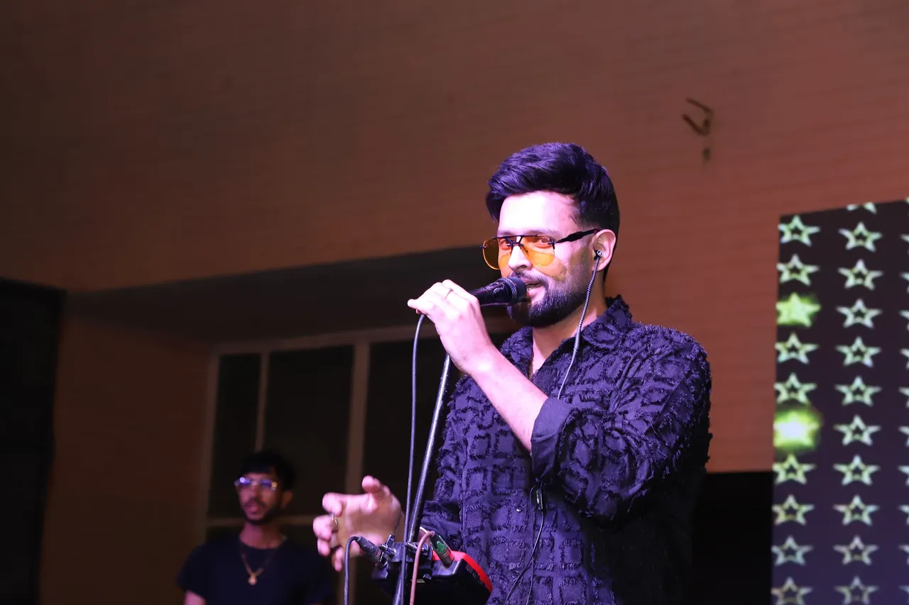 A singer performs at night in front of a starry backdrop