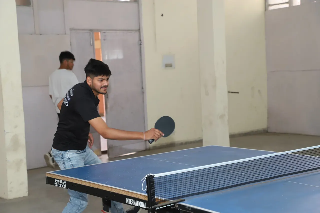 A table tennis player plays a forehand close to the net