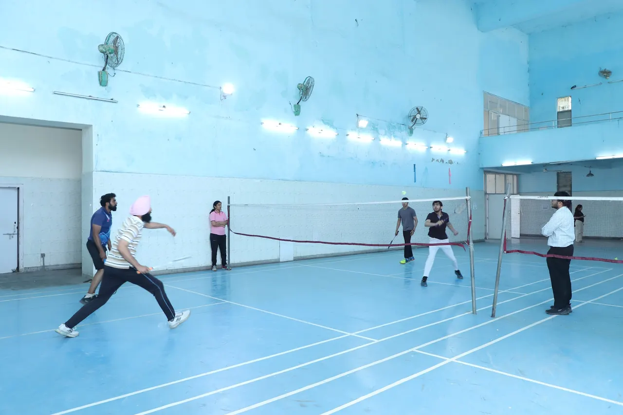 A badminton player smashes in the indoor hall