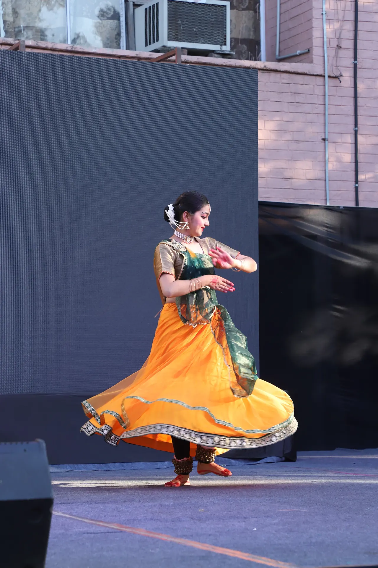 A classical dancer in an orange skirt spins on stage