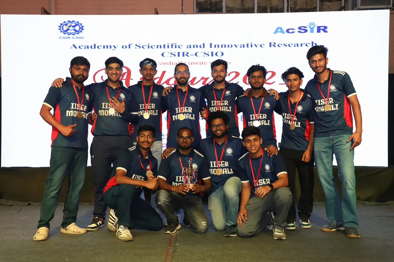 A winning team poses with trophies on stage