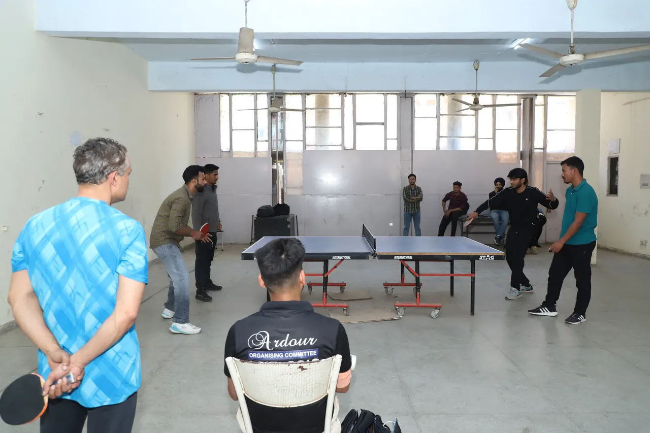 A volunteer in an Ardour Organising Committee shirt watches table tennis matches