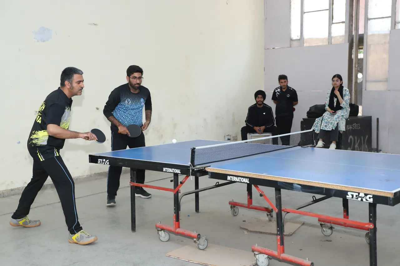 Doubles players at the table tennis table with spectators behind