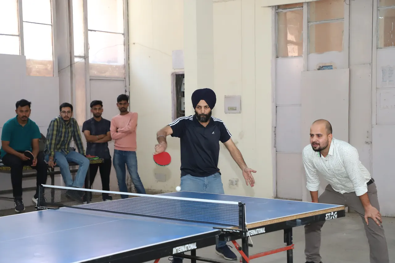 A table tennis player returns the ball as spectators watch from a bench