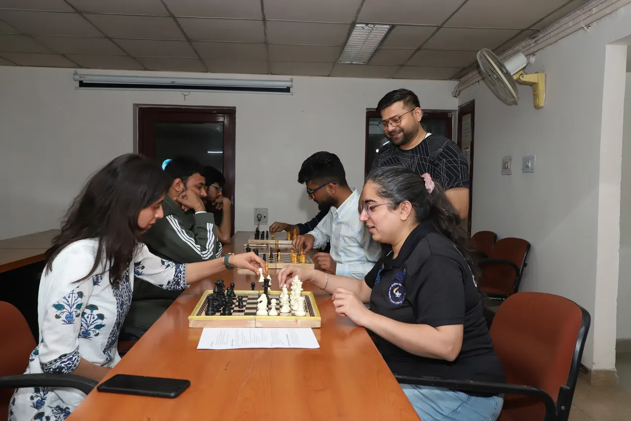Players concentrate over chessboards on a long table