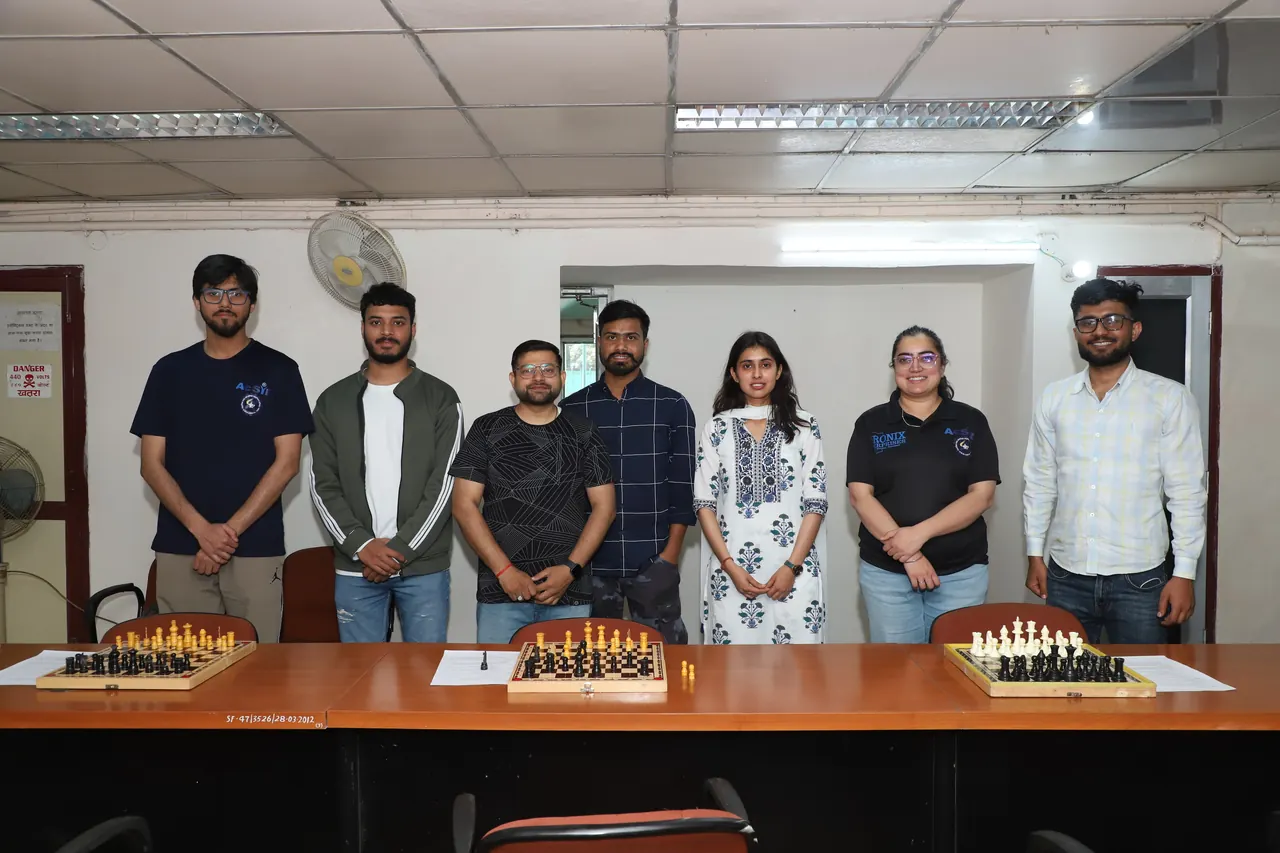 Chess participants stand behind a row of boards
