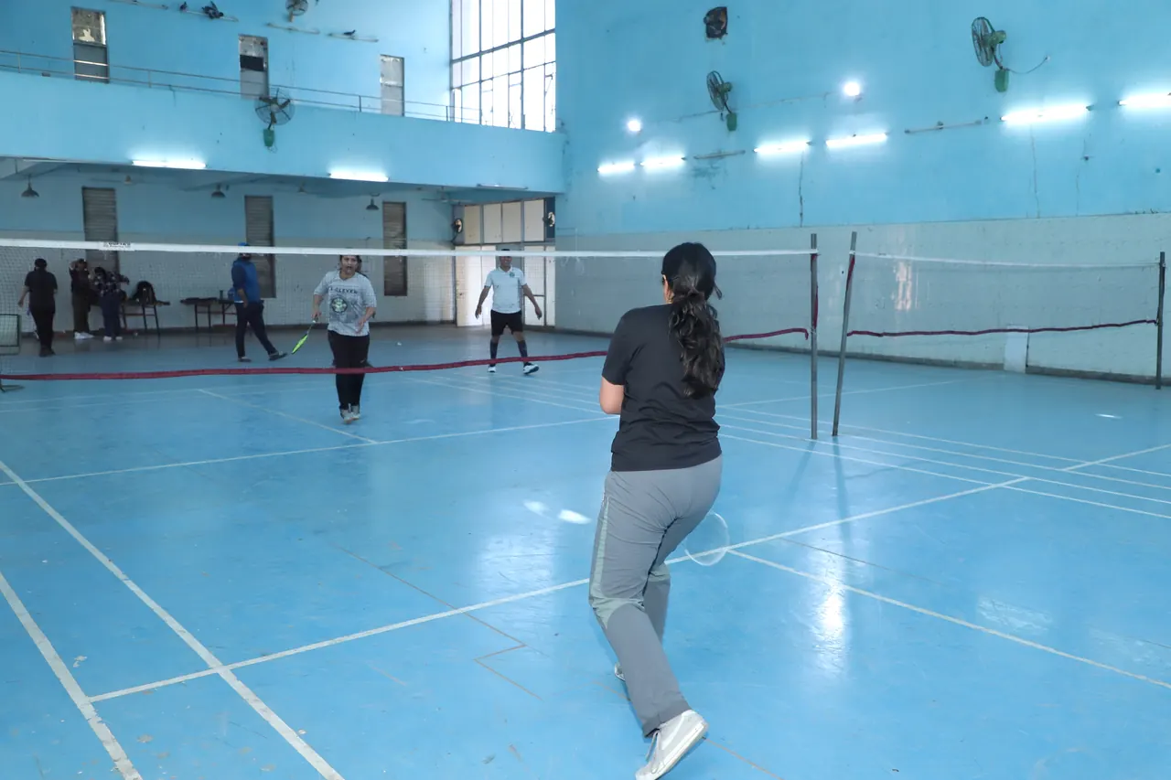 Players in a badminton rally in the indoor hall