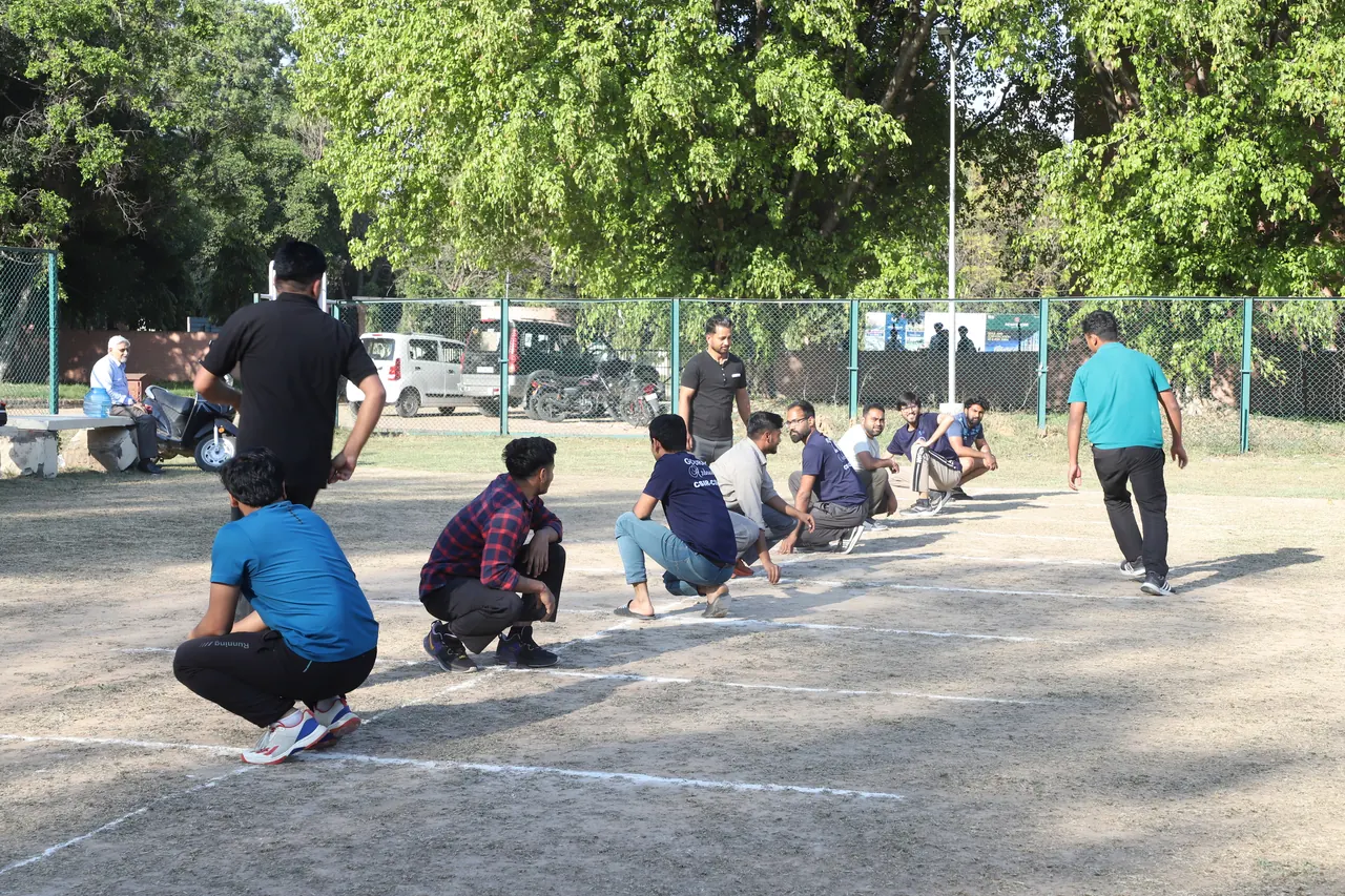 Kho kho players crouched in a line on the outdoor court