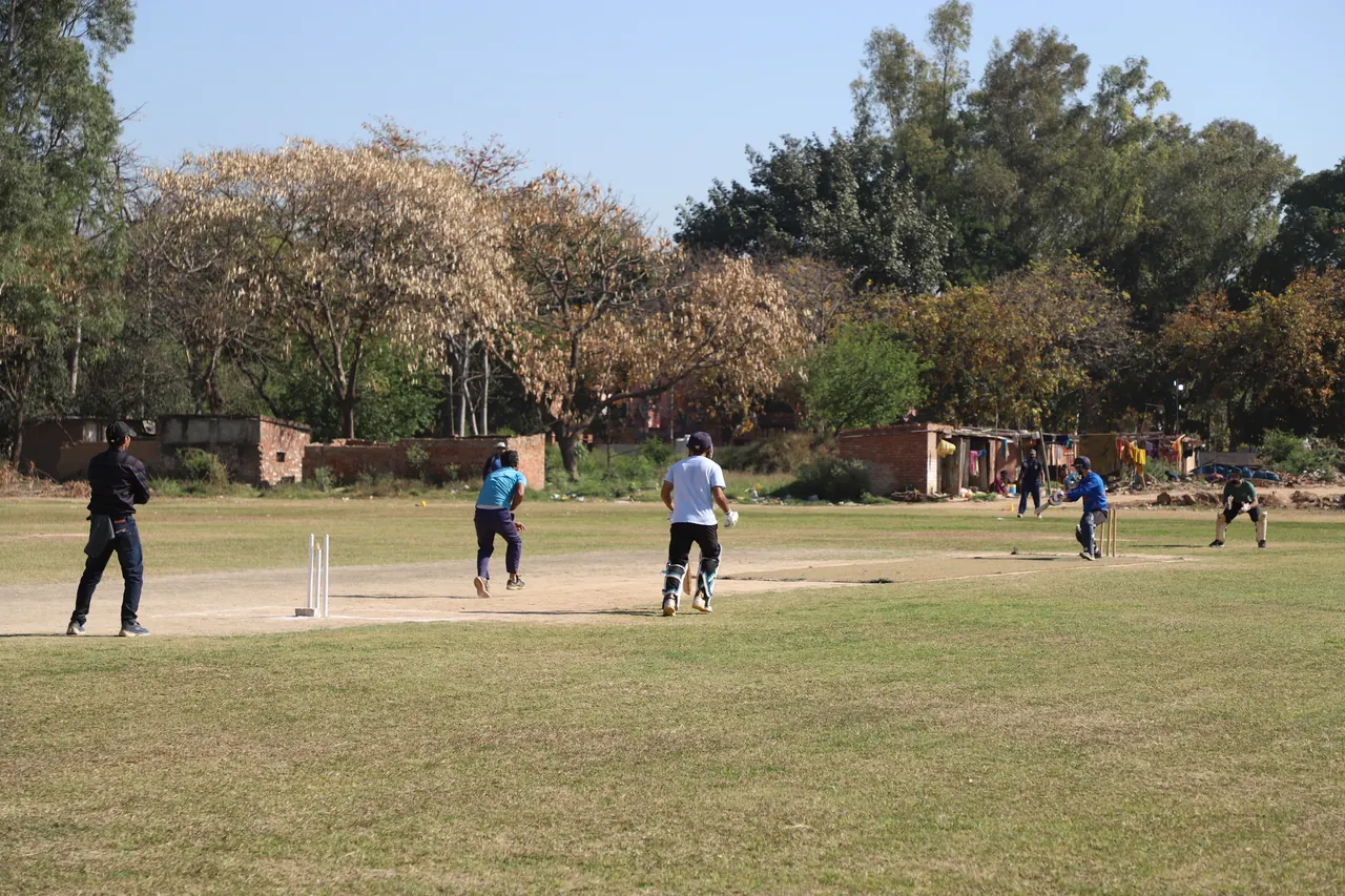 Fielders and a batter in position on the cricket ground