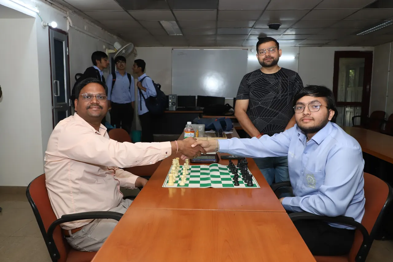 Two players shake hands across a chessboard