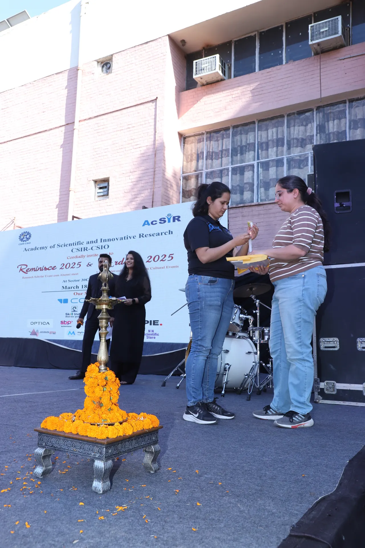 A ceremonial lamp decorated with marigolds in front of the Reminisce 2025 and Ardour 2025 stage