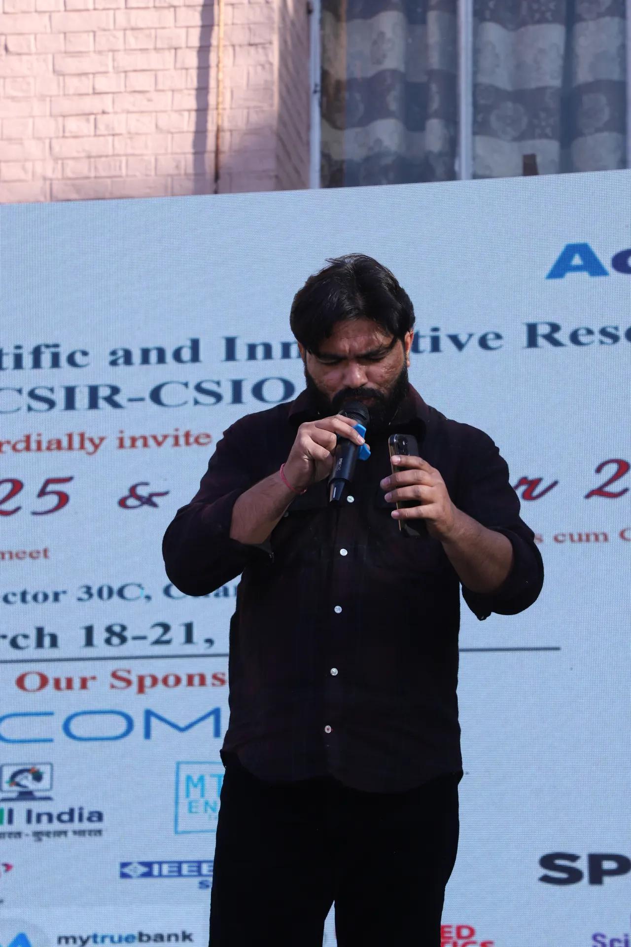 A performer at the microphone in front of the event backdrop