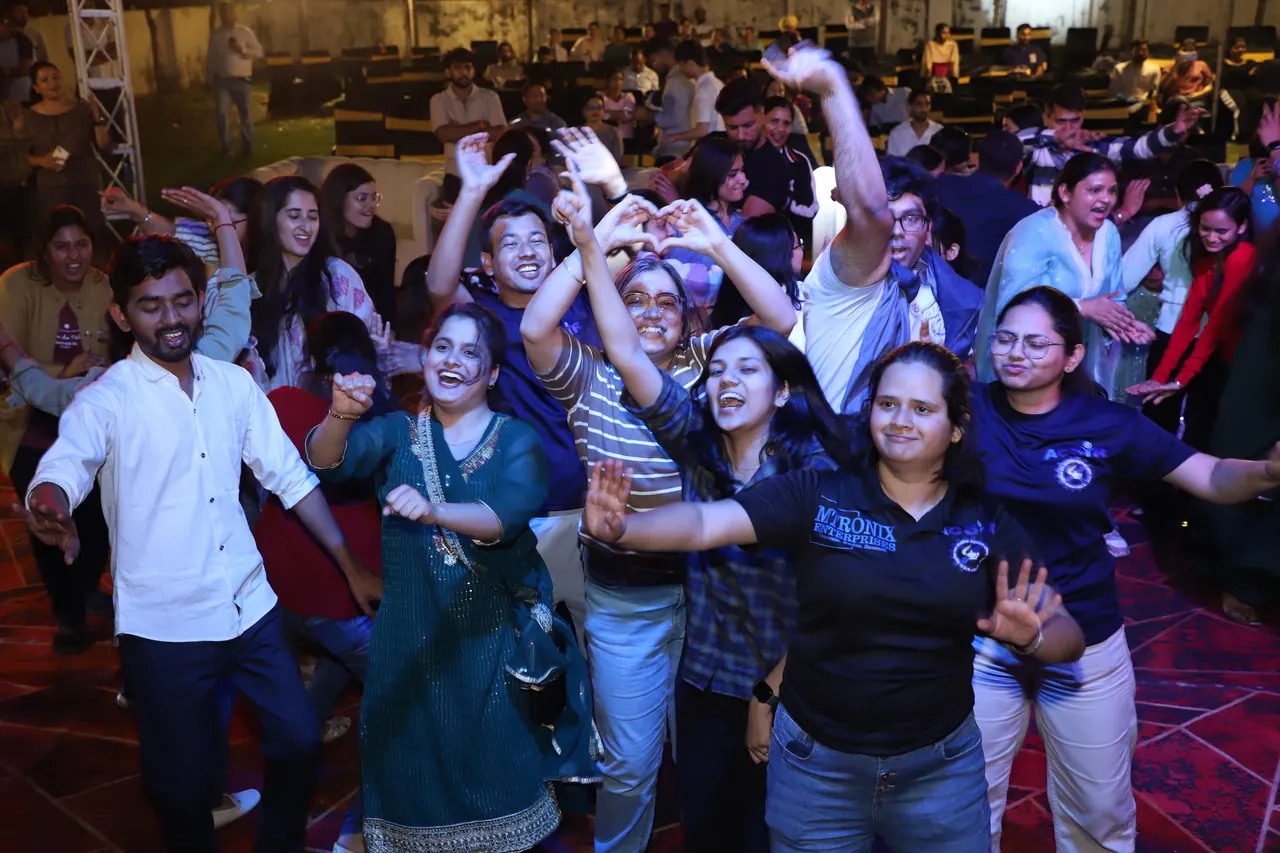A group of students dances and cheers at night
