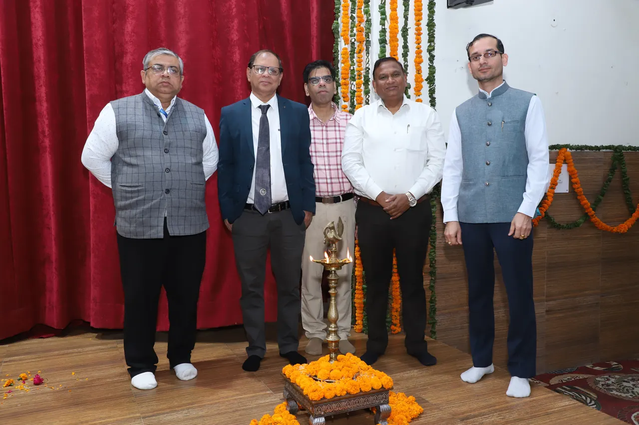 Guests stand together on stage beside the ceremonial lamp