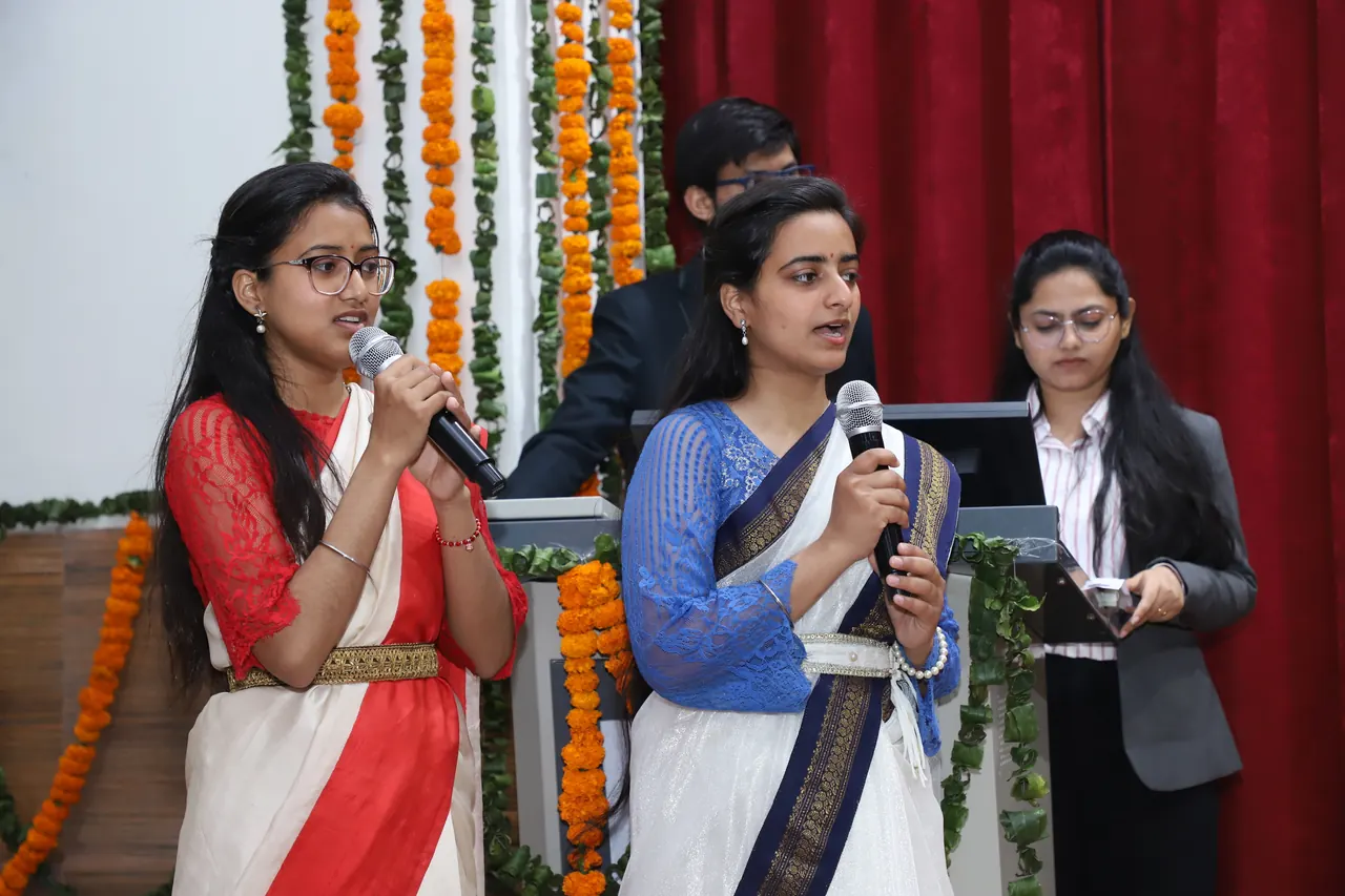 Three hosts speak from the podium at the opening session