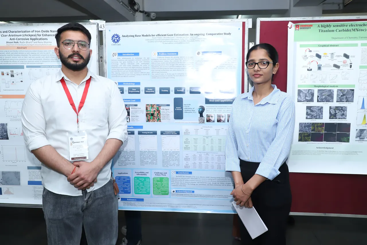 Two participants stand beside their posters on the display boards
