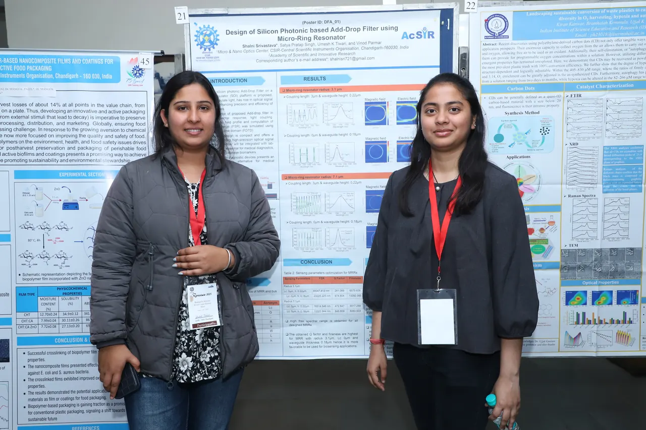 Two participants stand beside their posters on the display boards