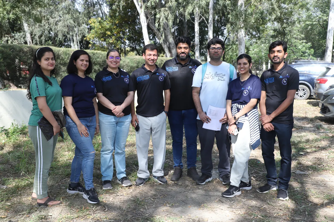 A group of participants poses outdoors under the trees
