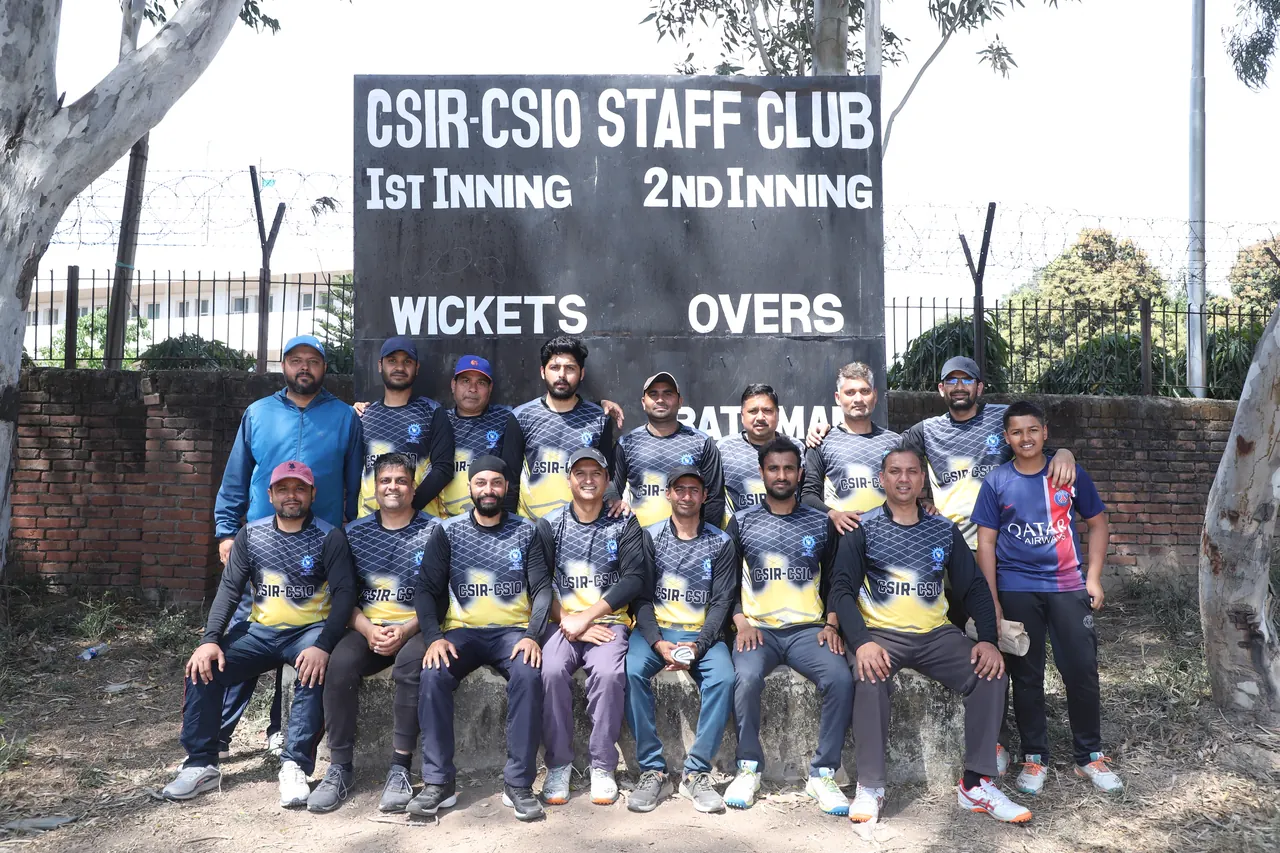 A cricket team poses in front of the CSIR-CSIO Staff Club scoreboard