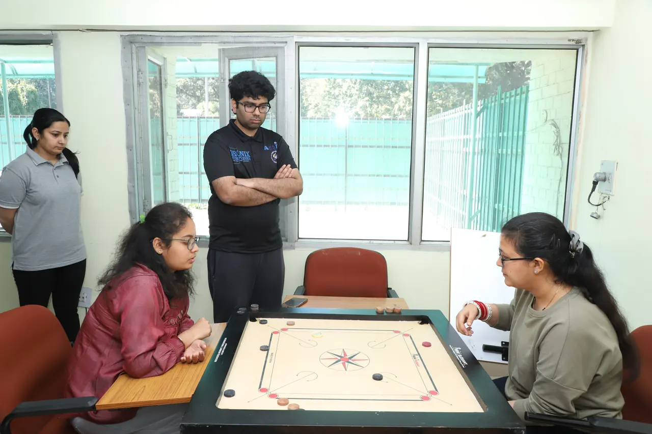 Two players face each other across a carrom board