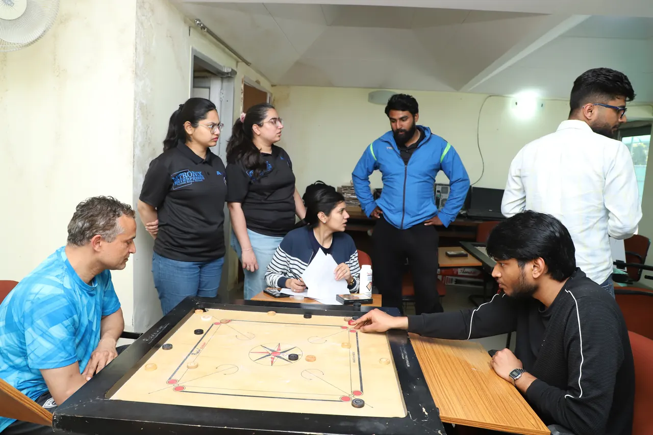 Players and onlookers around a carrom board