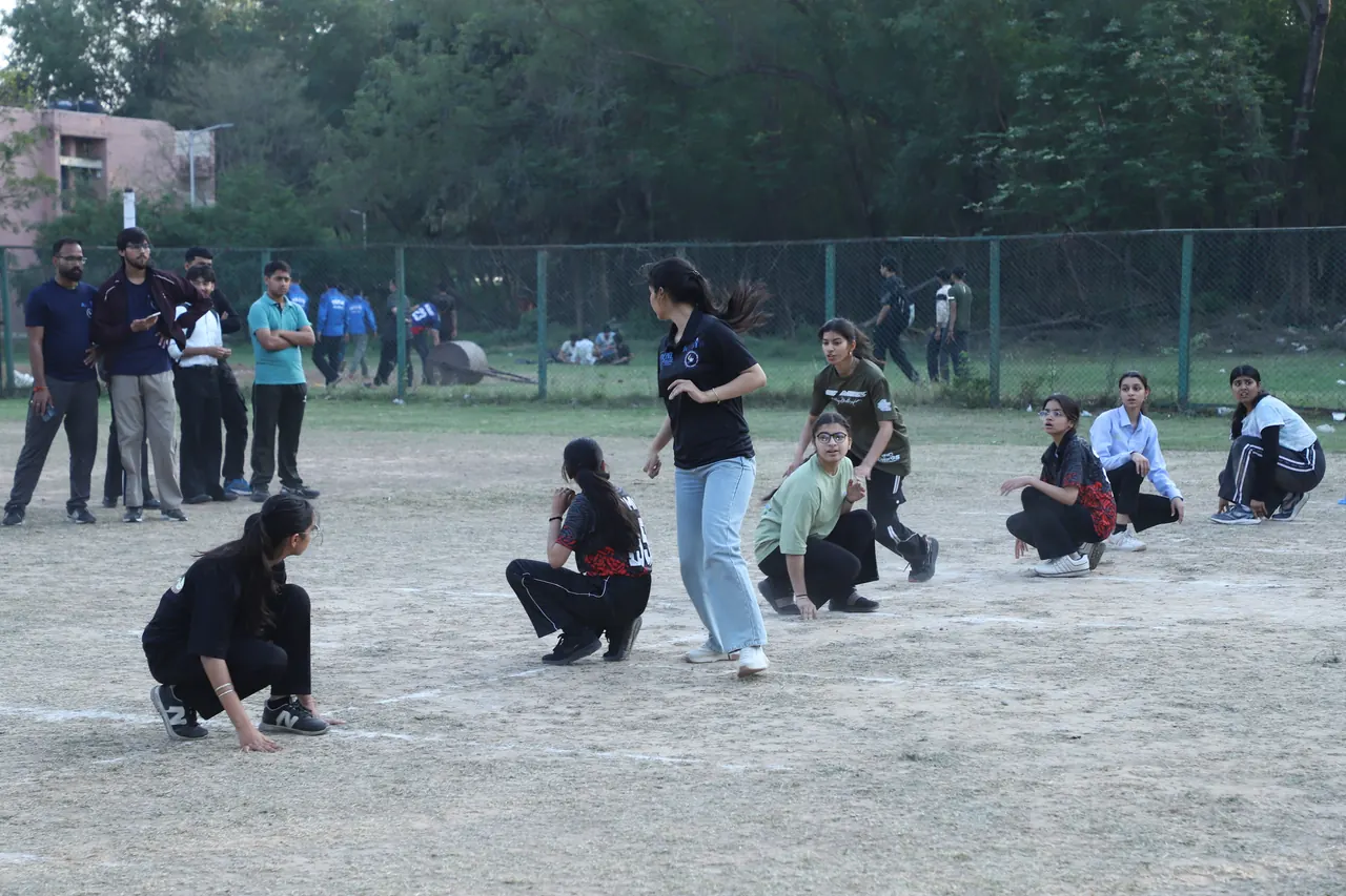 A kho kho chaser runs past crouching players