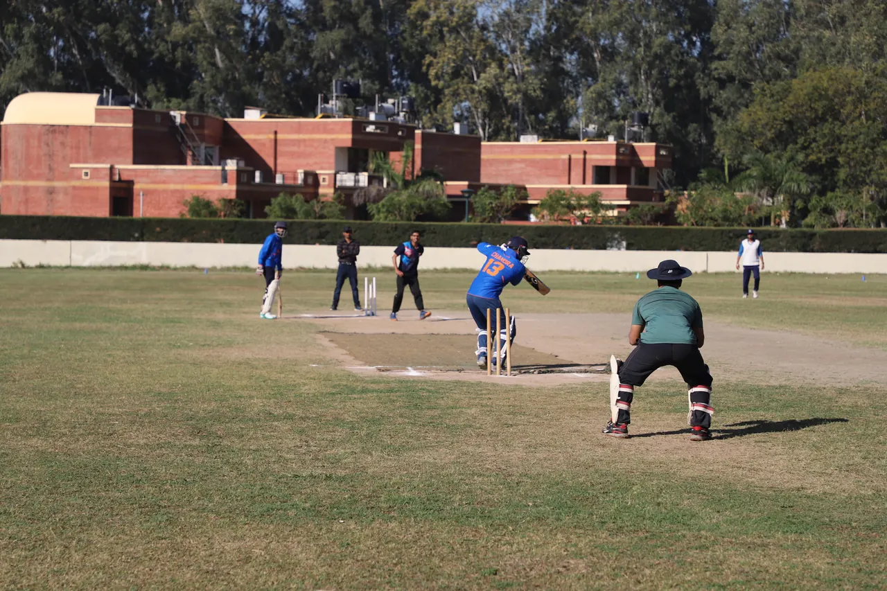 A batter and wicketkeeper at the crease on the campus ground