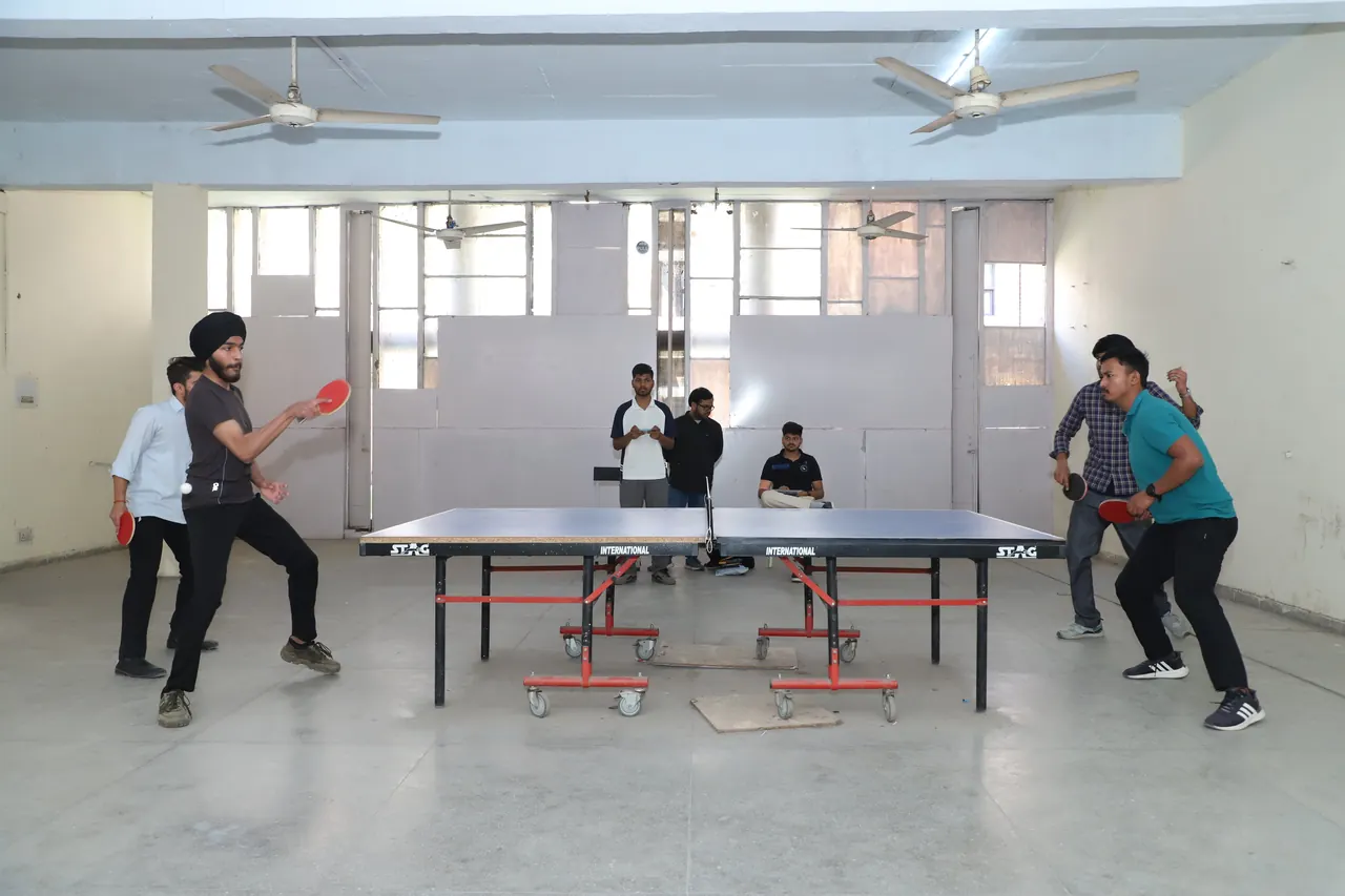 Players in a table tennis rally in the indoor hall