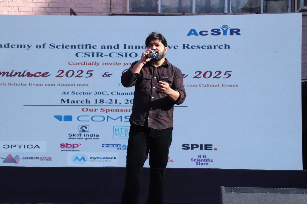 A performer at the microphone in front of the event backdrop
