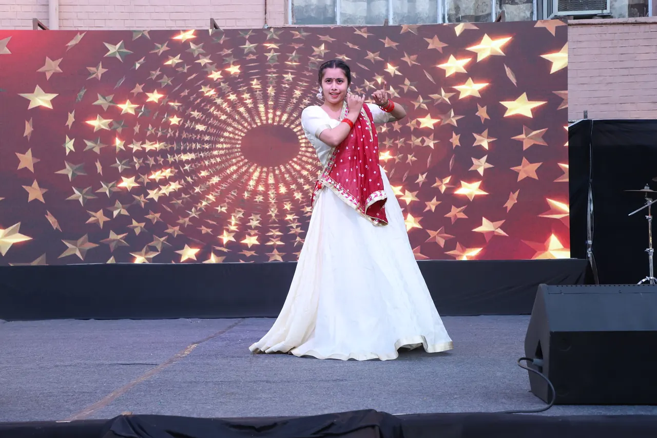 A dancer in white and red performs in front of a star backdrop