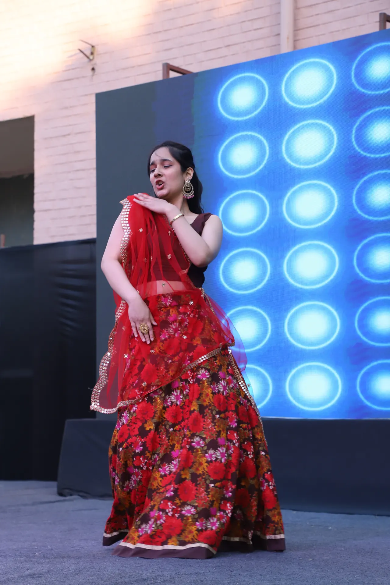 A dancer in red performs beside an LED wall