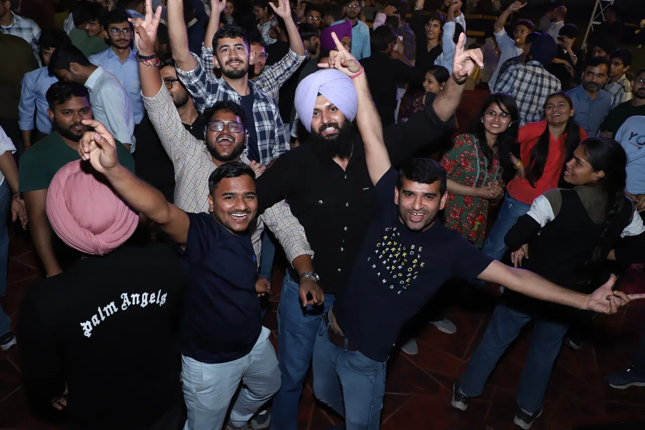 Participants dance with raised arms at night