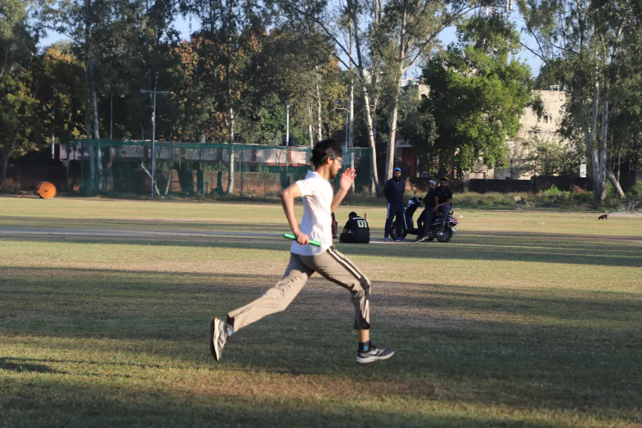 A runner sprints on the grass track