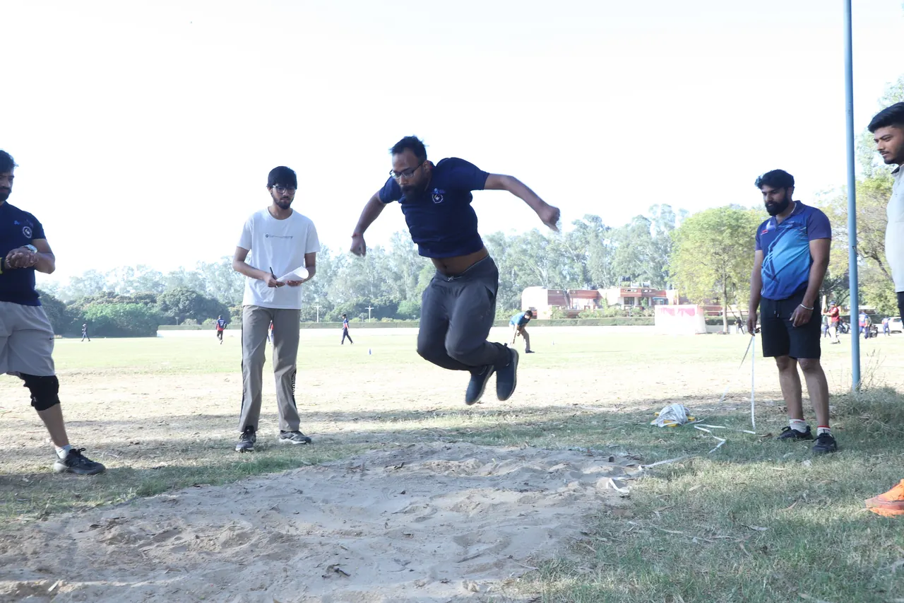 An athlete jumps as officials watch