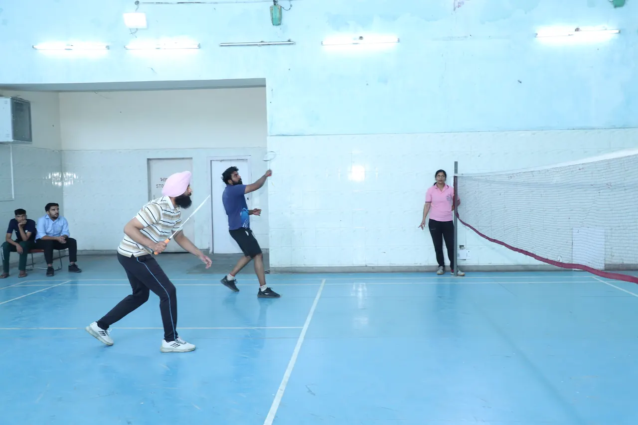 Badminton players in a rally on the blue court