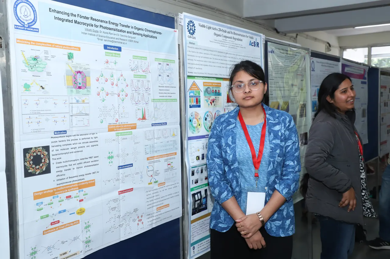 A participant stands beside her poster on the display boards