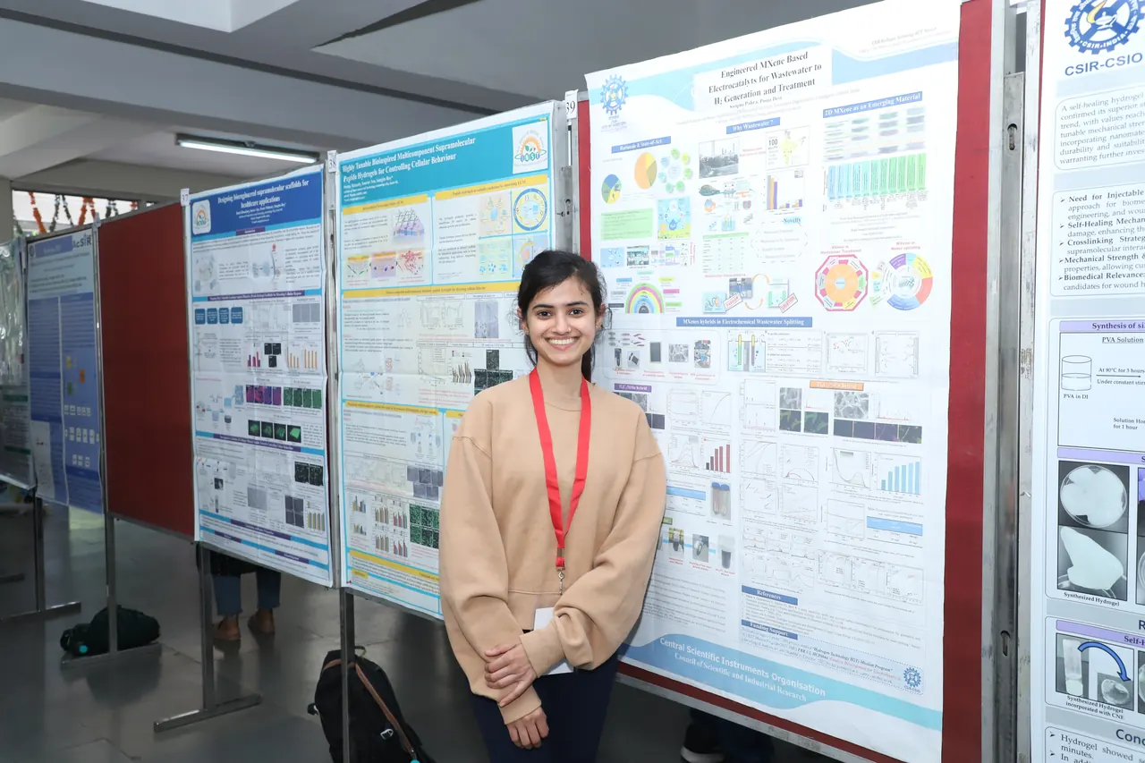 A participant smiles beside her poster on the display boards