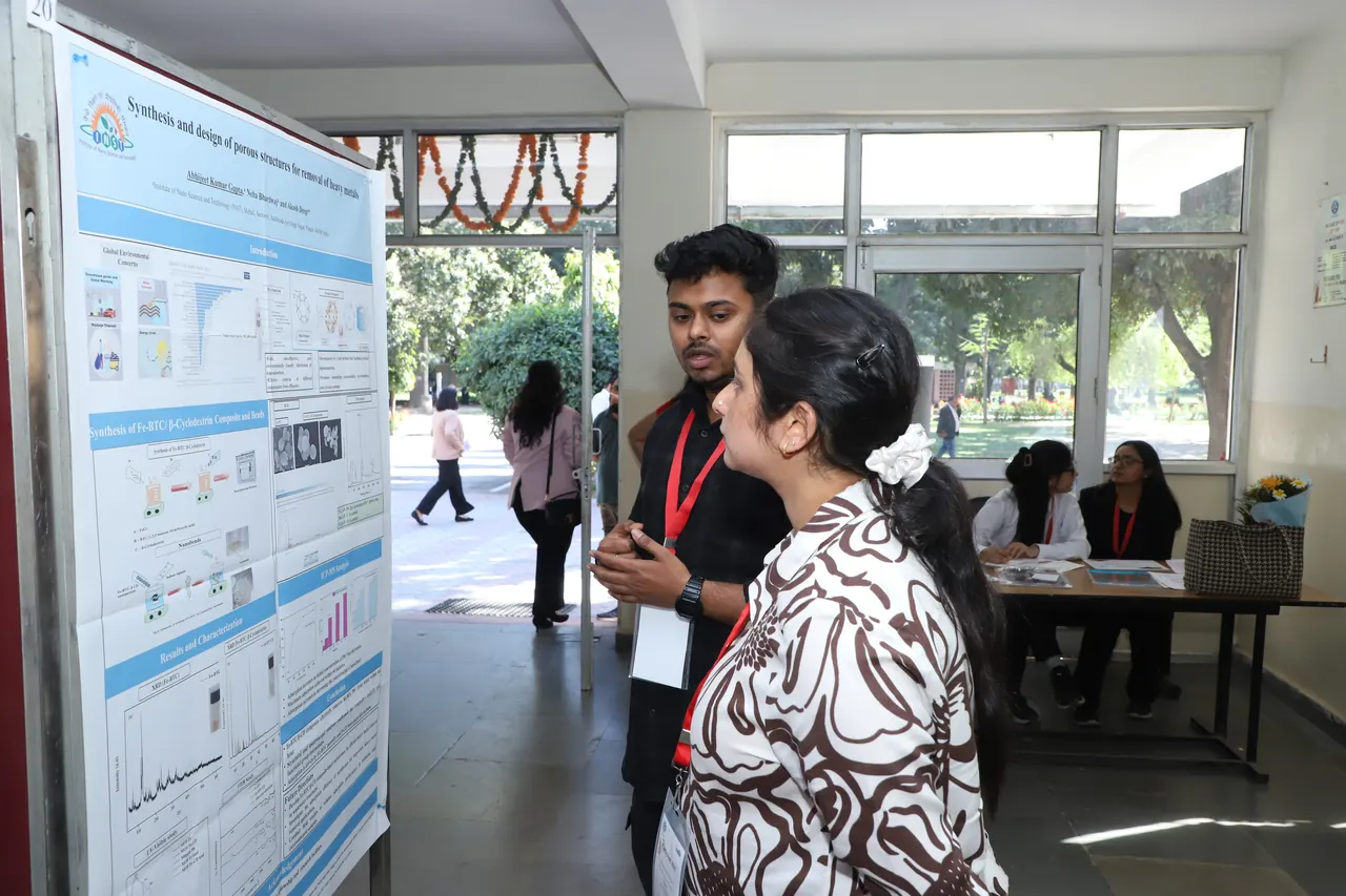 A participant discusses a poster with a visitor near the display boards