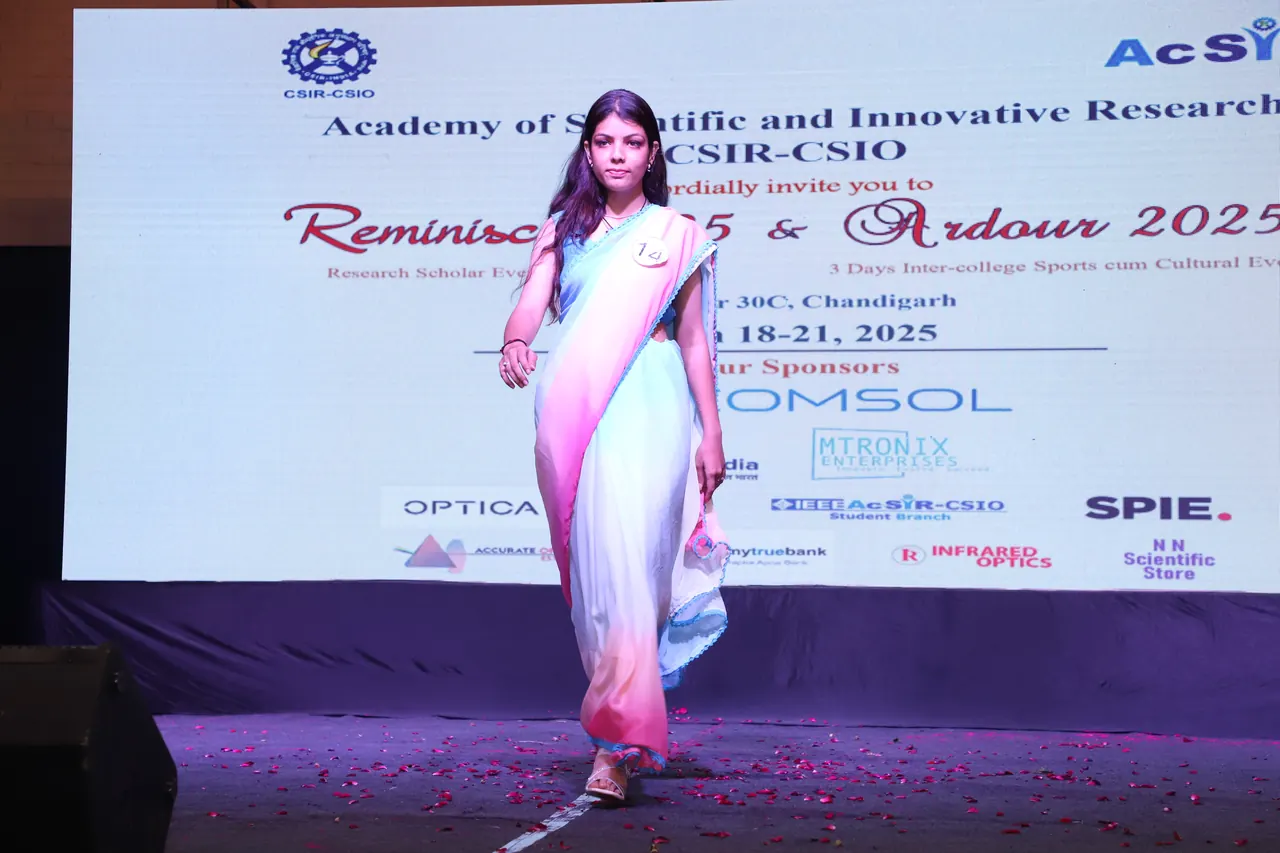 A participant in a pastel saree walks the ramp